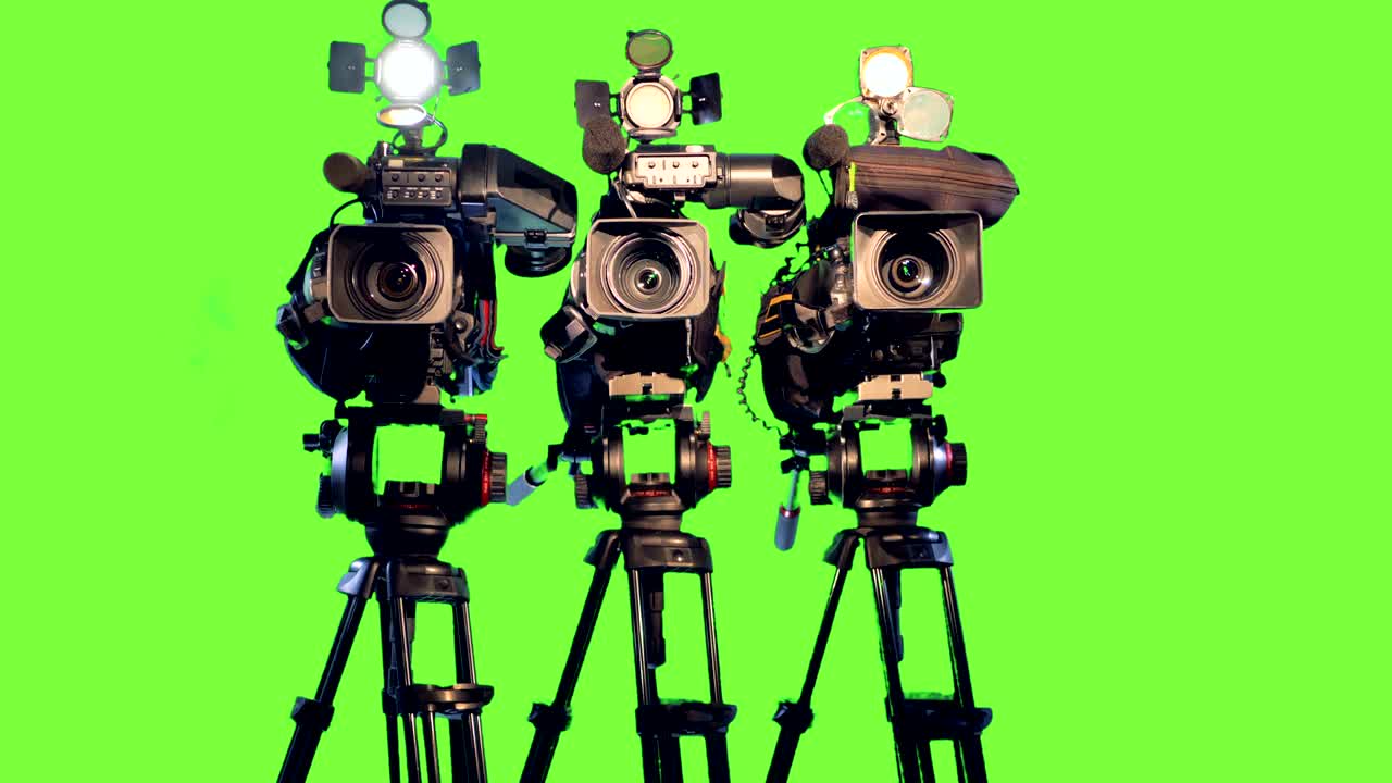três câmaras de vídeo profissionais em tripodes.