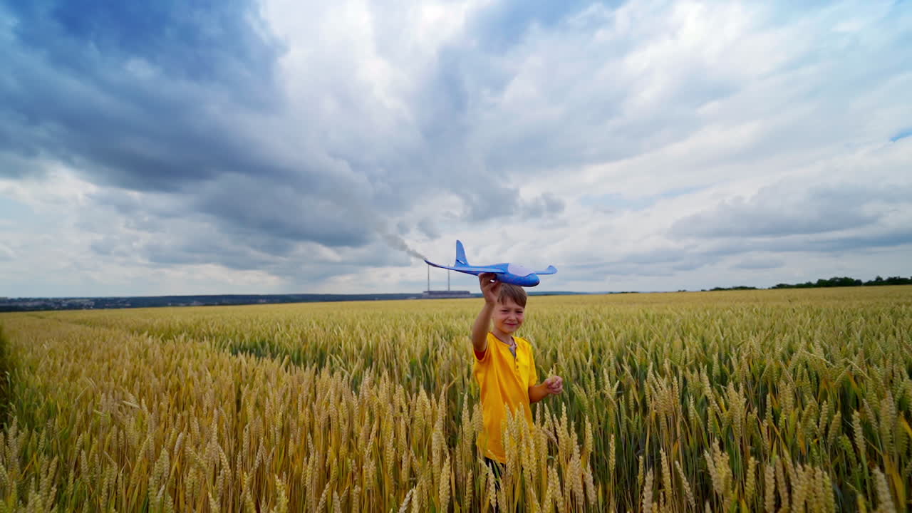 Boy playing with plane. Child running along wheat field at countryside, holding toy plane in hand