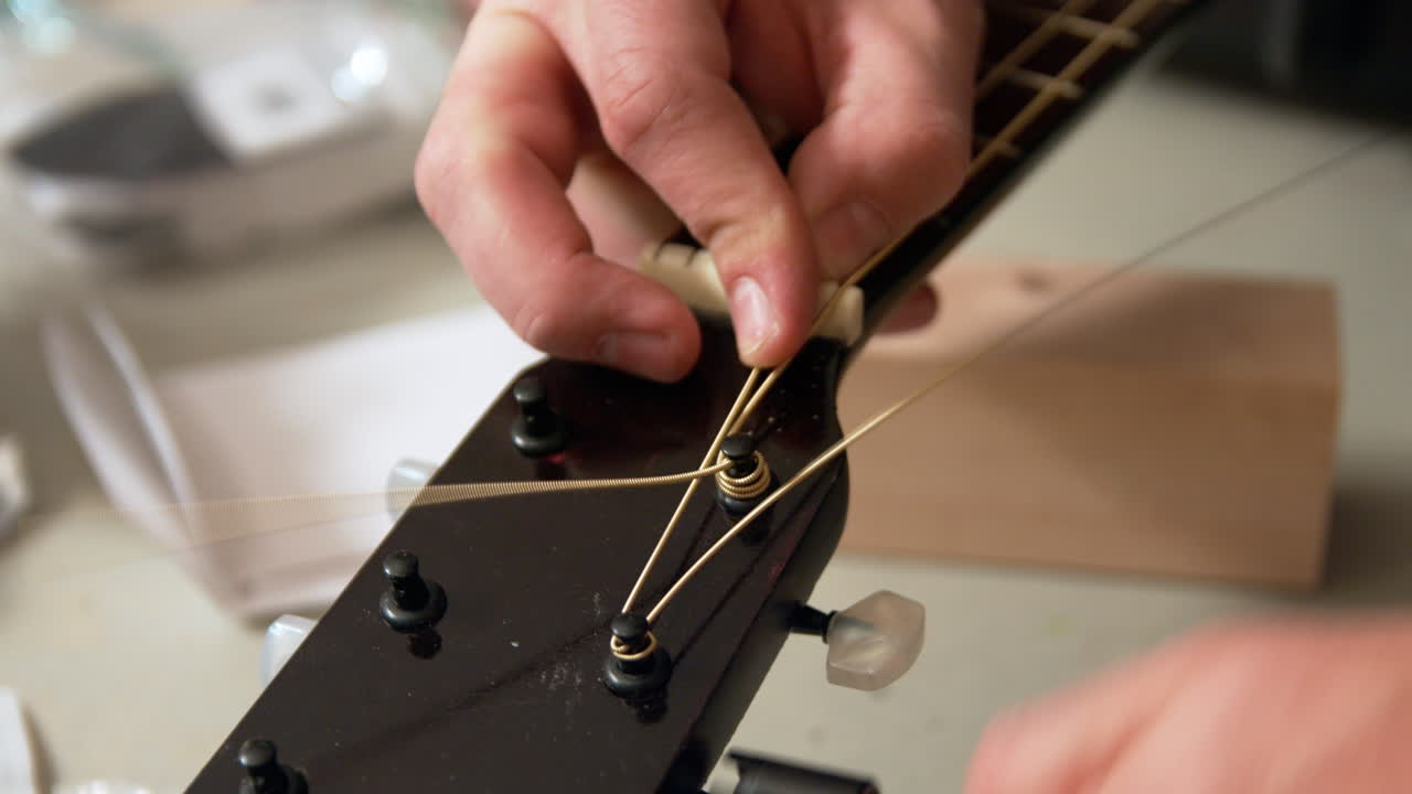 A hand twist or winds up a second new string on a guitar tuning peg