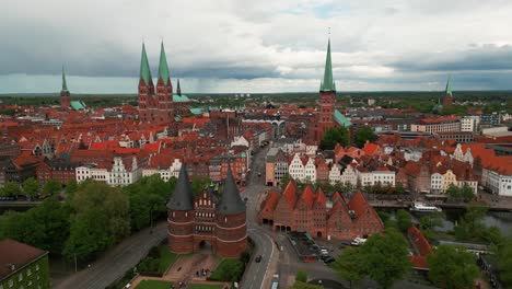 aerial shot around holstentor medieval gate with lubeck city center in the background on an overcast day in germany