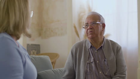 smiling senior man sitting on sofa with wife and talking