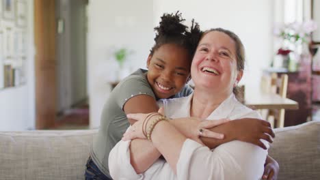 Porträt-Einer-Glücklichen-Kaukasischen-Frau-Und-Ihrer-Afroamerikanischen-Tochter,-Die-Im-Wohnzimmer-Lächelt