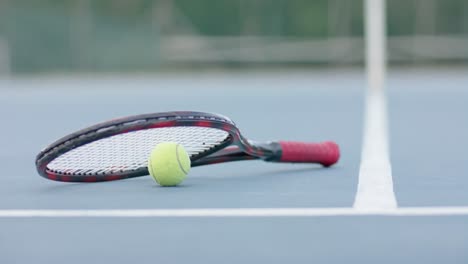 primo piano di una racchetta da tennis e di una palla su un campo da tennis all'aperto, in rallentatore