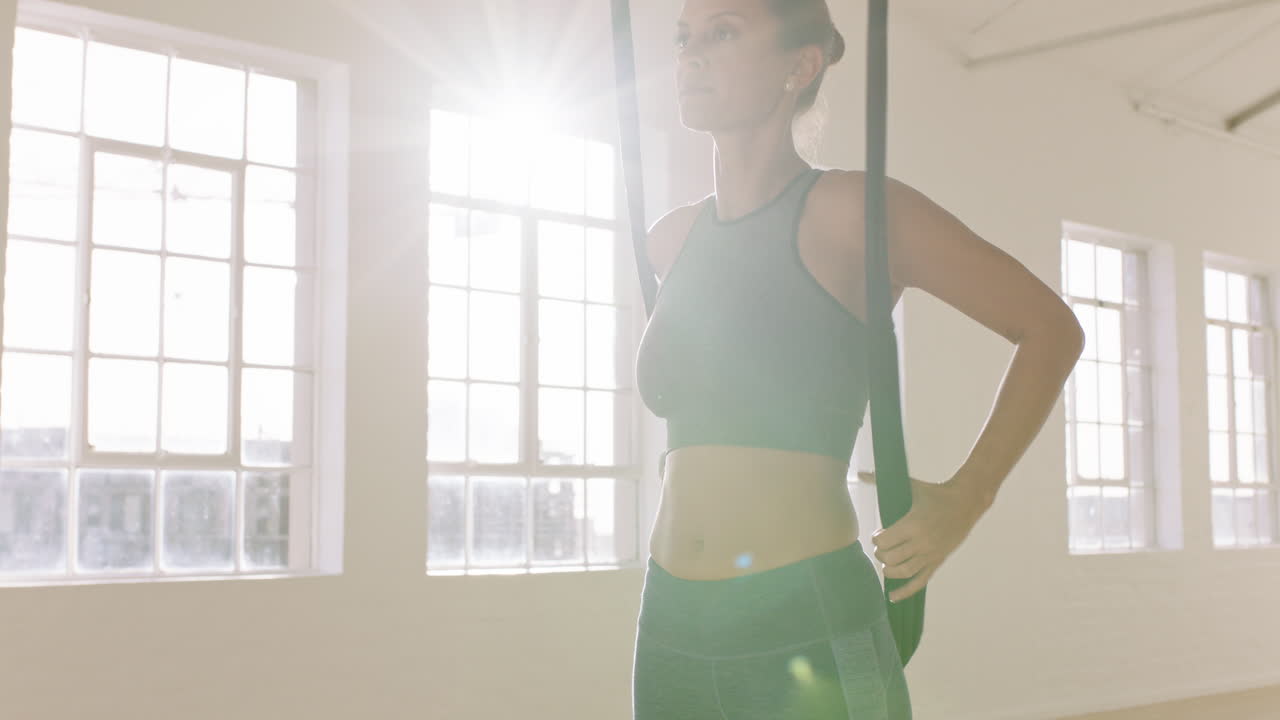 공중 요가 여성이 역전 나비 자세를 연습하고 하모크를 사용하여 거꾸로 매달려 건강한 피트니스 라이프 스타일을 즐기고 스튜디오에서 운동하고 해가 뜨면 명상하고 있습니다.