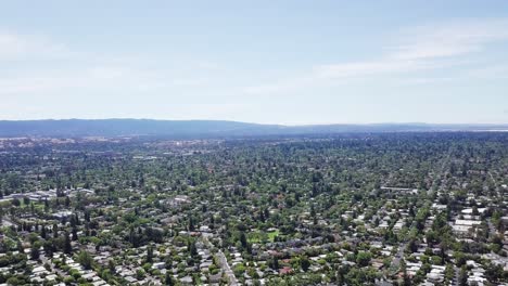 panoramic birds eye view of silicon valley suburbs with mountains in background and blue sky, crisp quality 4k high resolution aerial footage