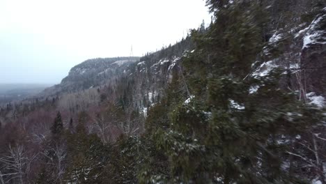 Flying-next-to-mountain-and-trees-to-show-off-this-mountain-during-a-snow-fall