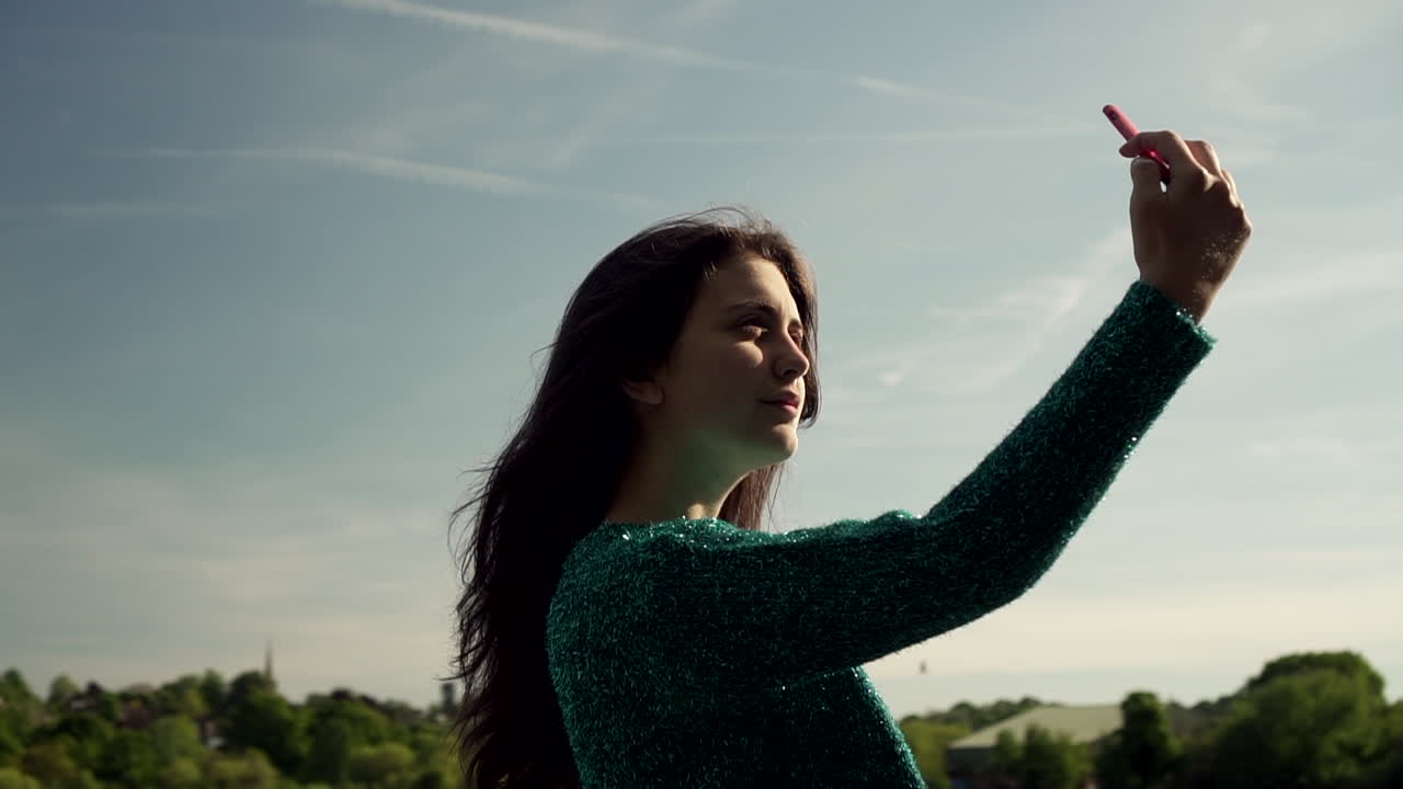 joven italiana con smartphone tomando selfie al aire libre en un parque en londres