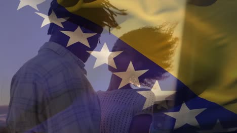 flag of bosnia and herzegovina waving over african american couple embracing at beach