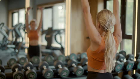 Chica-En-Forma-Seria-Haciendo-Flexiones-De-Bíceps-Con-Mancuernas-En-El-Club.-Mujer-Deportiva-Entrenando-En-El-Gimnasio