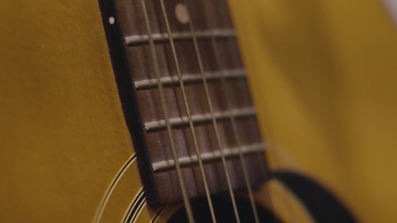 Plucking various strings on an old guitar in slow motion