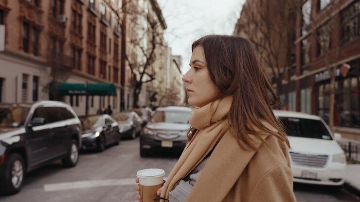 mujer caminando por la ciudad con café