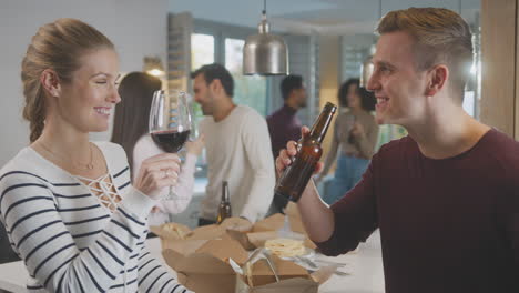 group of multi cultural friends enjoying drinks party with takeaway food at home together