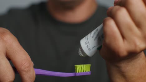 man applying toothpaste to toothbrush