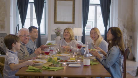 retrato de una familia feliz sentada en la mesa, posando y mirando la cámara durante una cena festiva en casa