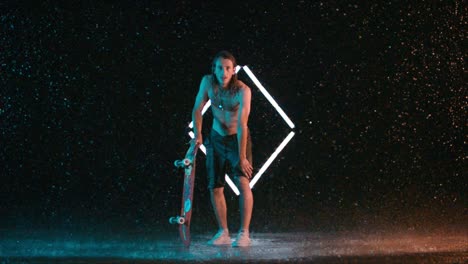 caucasian male skateboarder holding board in rain and looking at camera, slow motion