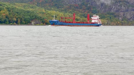 a cargo ship on the hudson river during fall in new york's hudson valley on a rainy day with low clouds