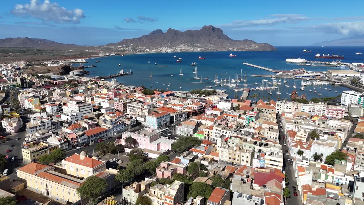 Scatto panoramico aereo della baia di Mindelo e del porto della città a Sao Vicente, Capo Verde. Ampia veduta del porto marittimo, edifici colorati e aspre montagne vulcaniche in lontananza.