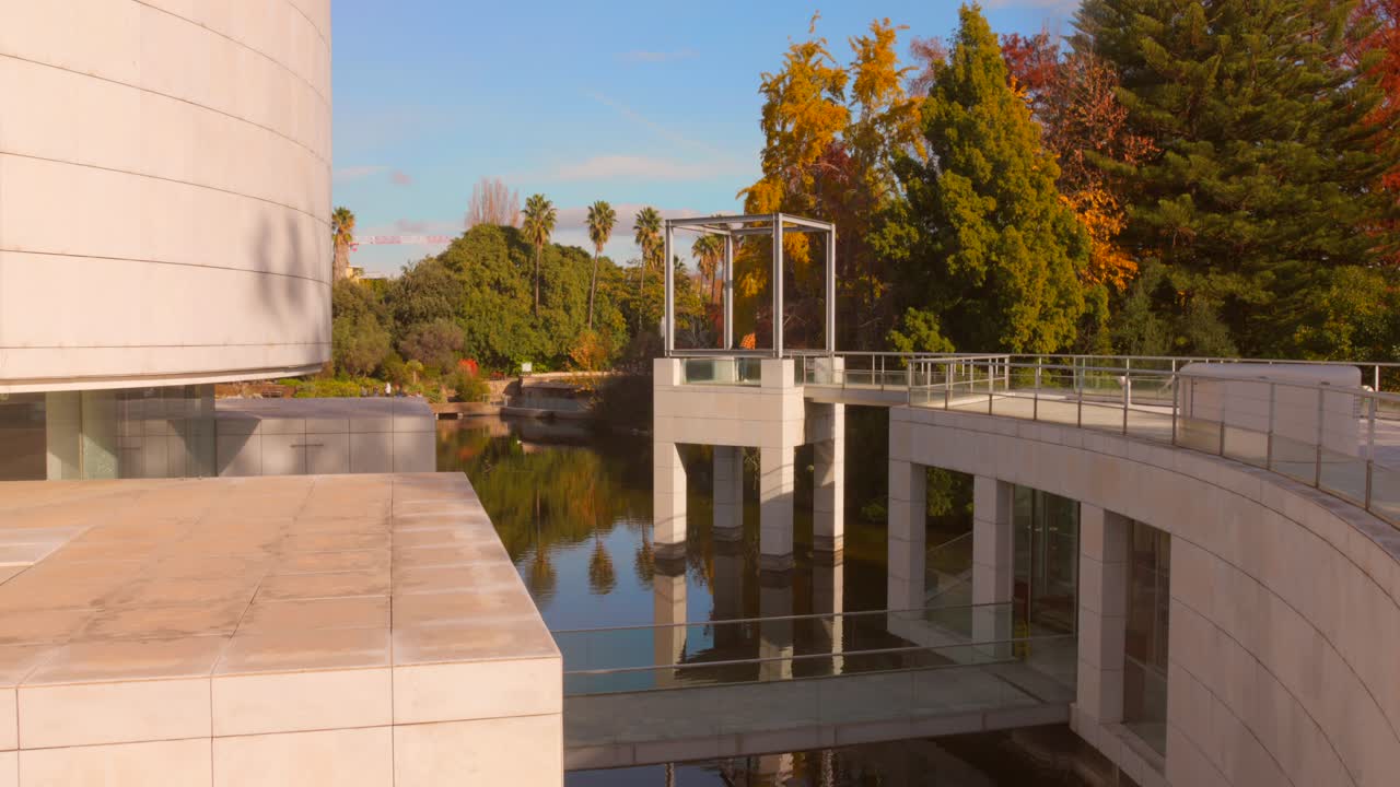Puente peatonal y estructura moderna del Museo de Arte Asiático de Niza, rodeado de árboles y agua en un día soleado