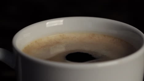 una gota cayendo en una taza de café. primer plano sobre un fondo negro.