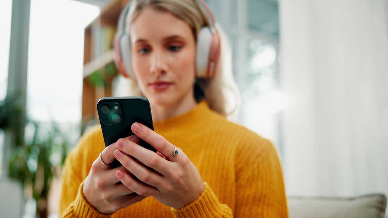 Woman listening to music on her phone with headphones at home