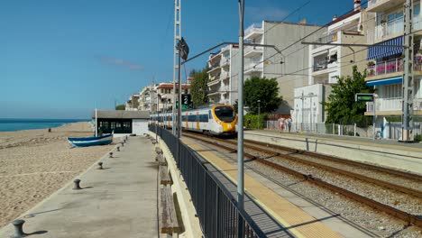 rodalies train on the costa del maresme in barcelona mid-distance passing by the beach overlooking the sea