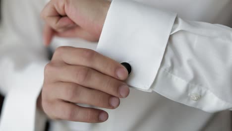 handsome groom man fixes his cuffs on a jacket with cufflinks. businessman