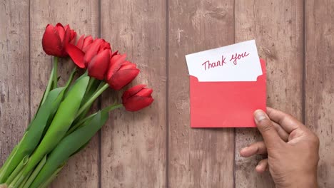 red tulips and thank you note on wooden background