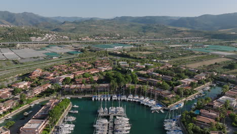 aerial view of a scenic marina with yachts, coastal town, and mountains