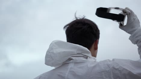 Man-putting-off-protection-mask-standing-on-the-edge-of-the-roof-with-smoke-stick