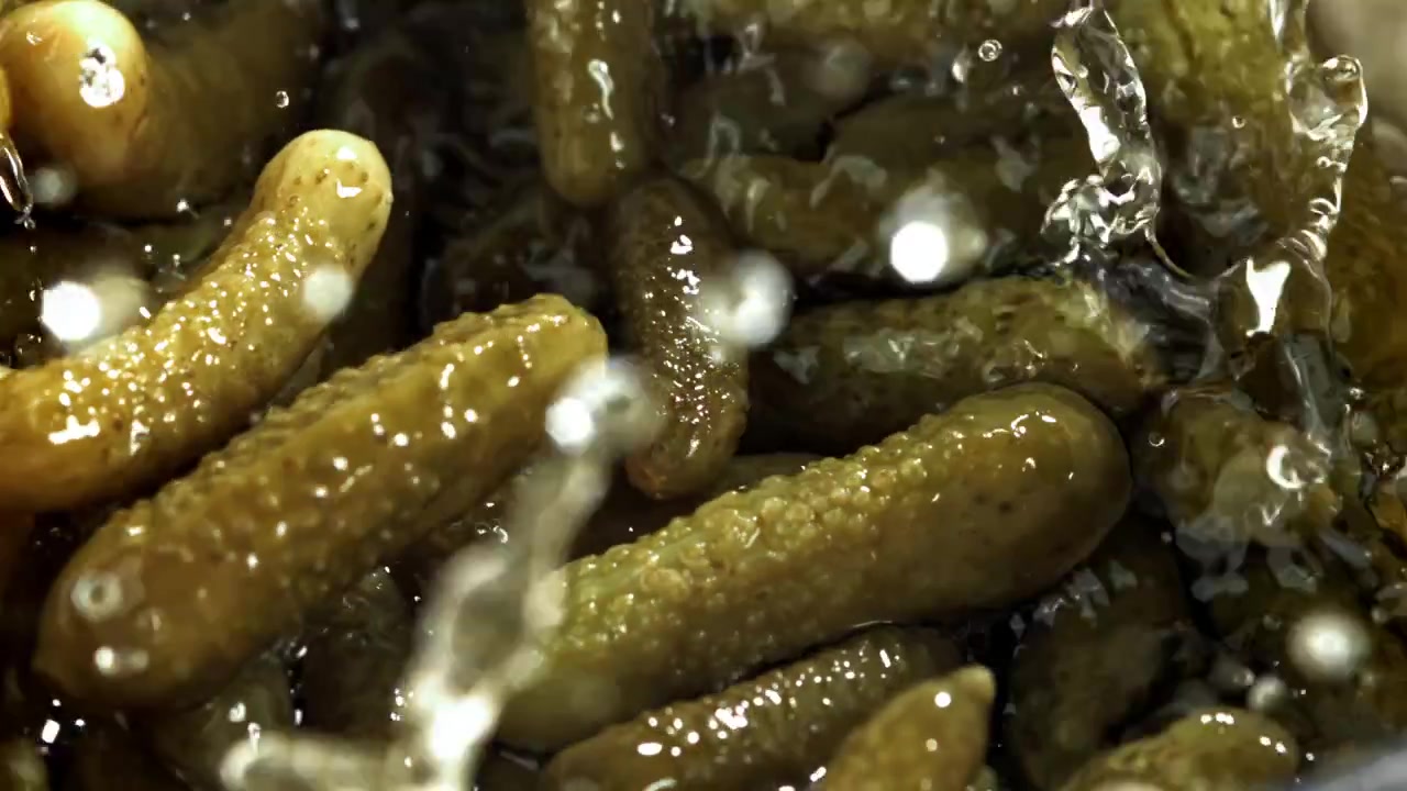 Cornichons frais tombant dans la saumure avec des éclaboussures au ralenti