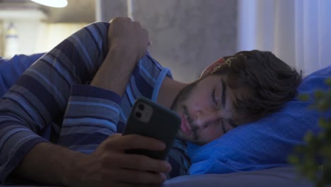 The-man-looking-at-the-phone-at-night-is-dozing-in-his-bed.