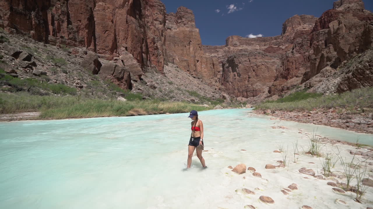 mujer joven caminando en barro blanco por aguas turquesas del pequeño río colorado, parque nacional del gran cañón, arizona usa, cámara lenta