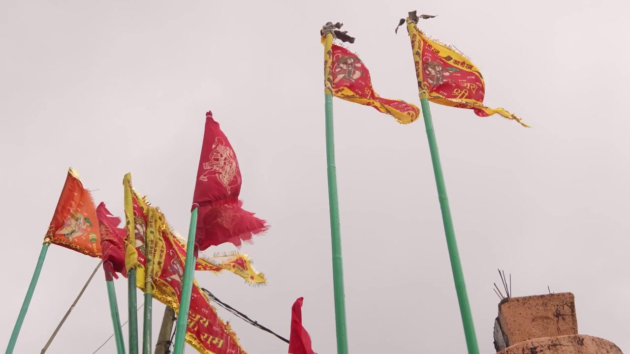 Traditional saffron and red religious flags waving in the wind at the sacred Ganga Talao temple complex, a significant Hindu pilgrimage site located in the mountainous highlands of Mauritius.
