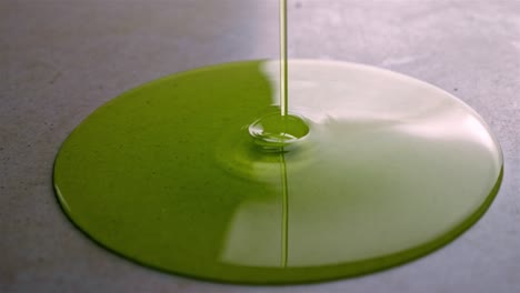 pouring thin green fluid on table spreading on a circular shape