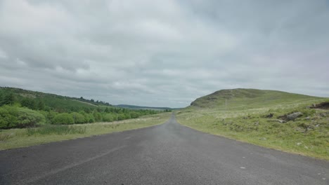 A-single-track-road-between-green-lush-mountains-and-trees,-locked-off