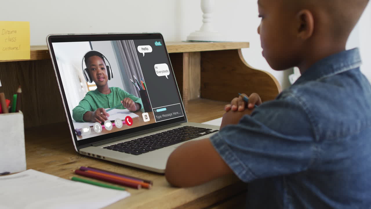 Schoolboy using laptop for online lesson at home, with schoolboy and web chat on screen