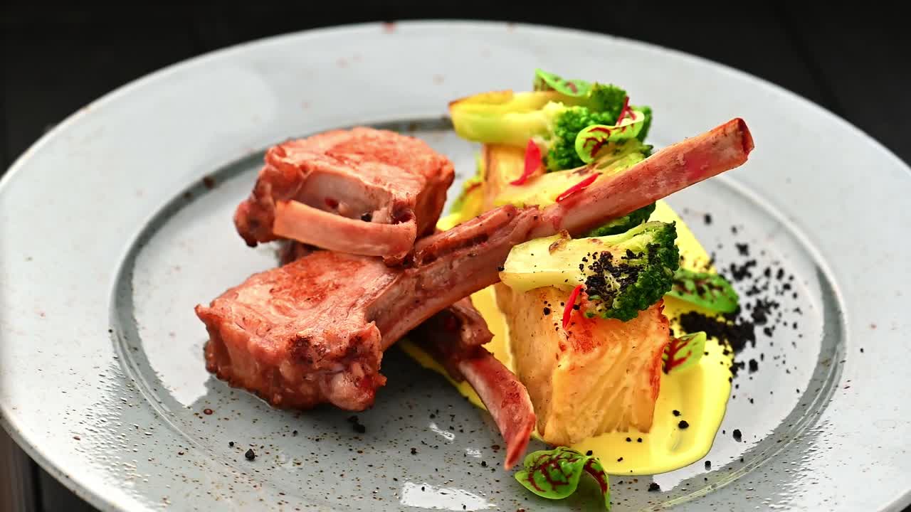 Lækre lammekoteletter serveret med grøntsager og tilbehør på en tallerken. En tallerken med lammekoteletter, broccoli og polenta som tilbehør viser et veltilberedt måltid.