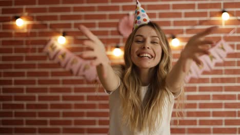 retrato de una mujer celebrando su cumpleaños mirando a la cámara positivamente y soplando un beso en el aire