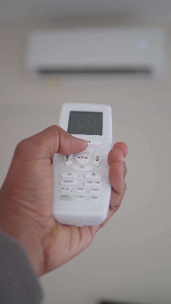 Person Using Remote Control to Adjust Air Conditioner