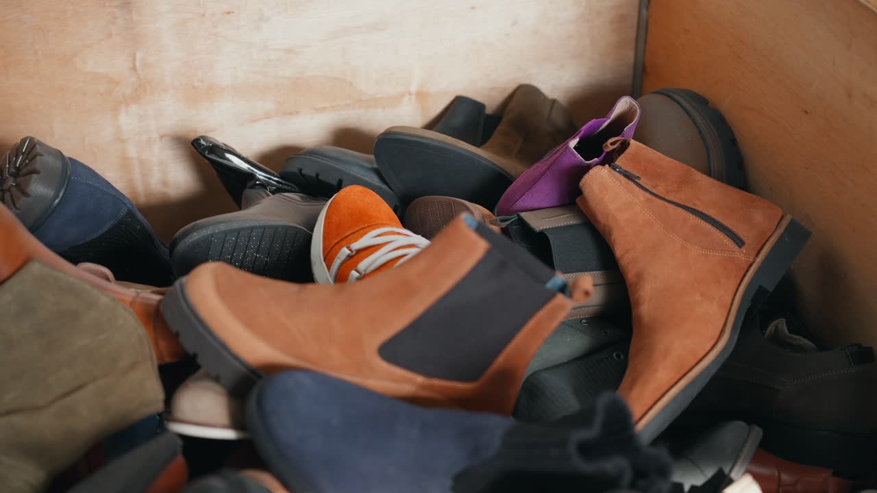 Mixed shoes piled together inside wooden container