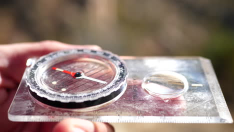 close up on a compass in the hands of a lost hiker being used in an emergency survival situation to find the trail and location