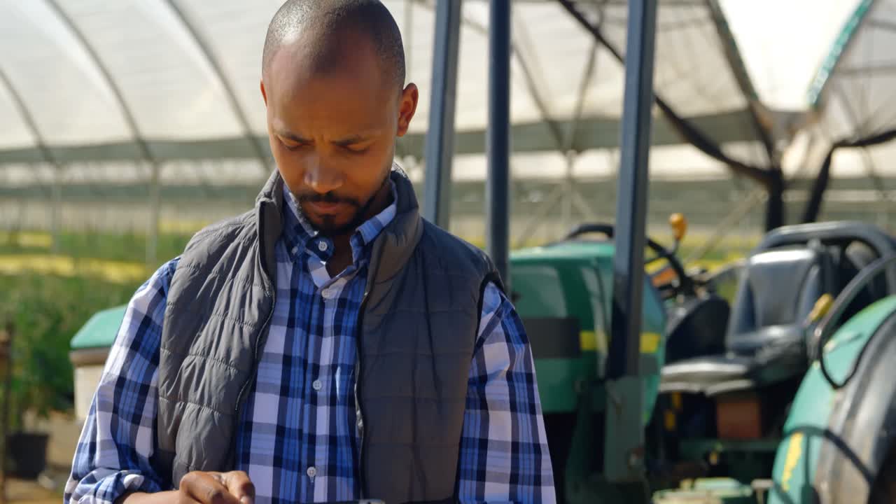 Homme utilisant une tablette numérique dans une ferme de myrtilles 4K