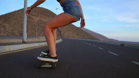 captured in slow motion, a woman wearing shorts skates along a road at sunset, with mountains and a stunning sky enhancing the scene