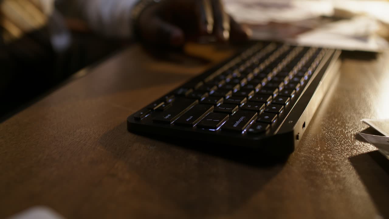 Person typing on a keyboard at a desk at night