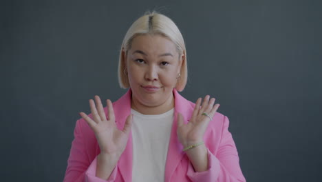 woman in pink blazer with hands up