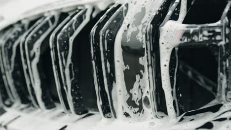 soap and water falls between twin kidney grille of a car forming an interesting little cascade with reflections