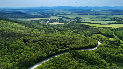hilly roads in lush scenery. aerial view showcases green hills and winding roads under a clear sky in a serene rural area