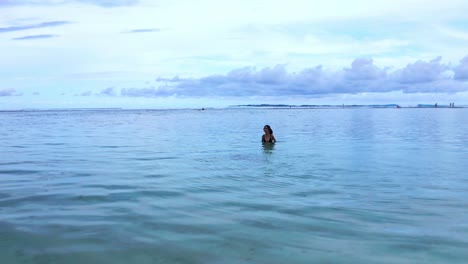 a woman in a crystal clear water of gunung payung beach in bali indonesia