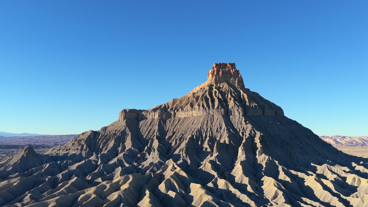 Un drone cattura la spina dorsale netta e scheletrica di una vetta planetaria desolata. Le ombre profonde e le antiche creste grigie di Factory Butte creano una cupa atmosfera aliena su un mondo lontano.