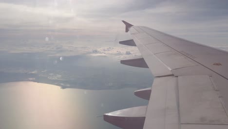 view of sky from inside airplane cabin while flying over cloud sky scape through the window with wing view in daytime